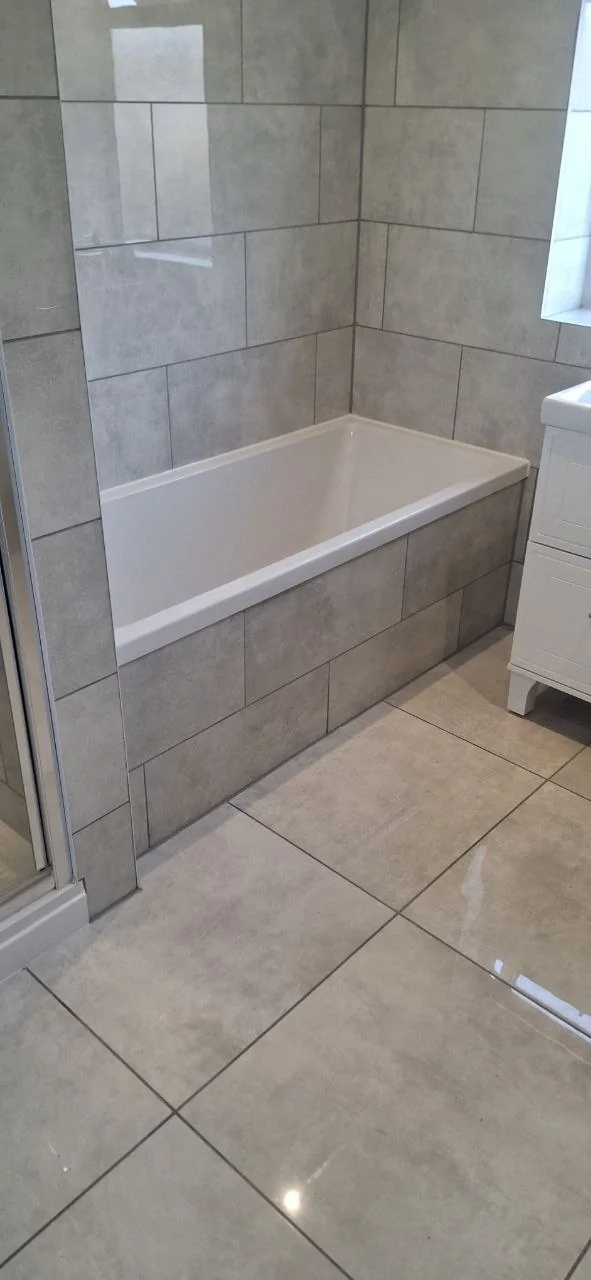 Bathroom tiling with grey tiles and bath installation — bathroom fitters Surrey