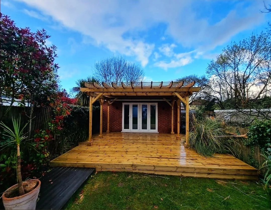 New timber decking and pergola after installation with blue sky — garden builders Hampton SW London
