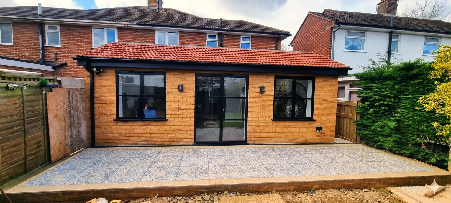 Completed rear extension with golden brick, bifold doors and decorative patio tiles — extension builders SW London