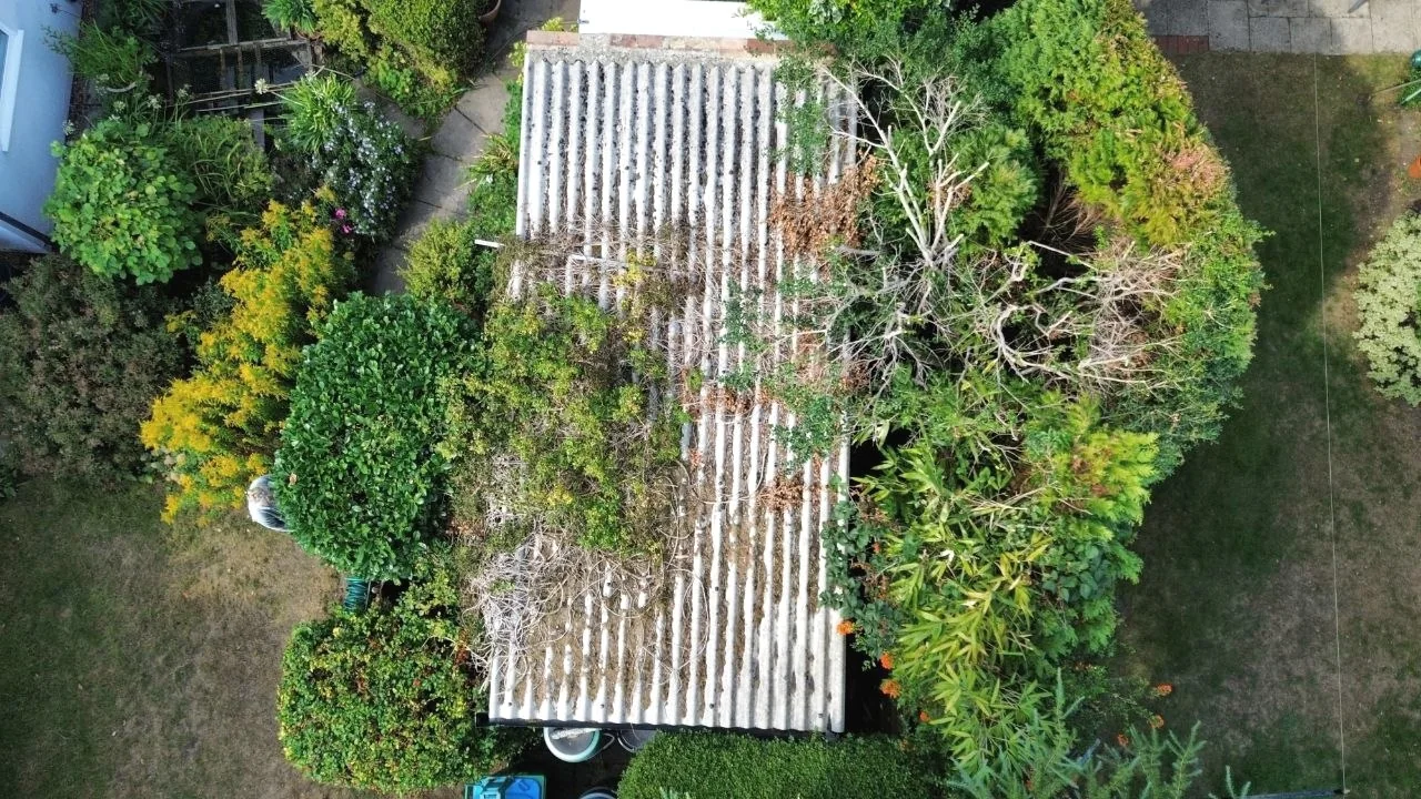Old corrugated flat roof before replacement — worn moss-covered roof Surrey