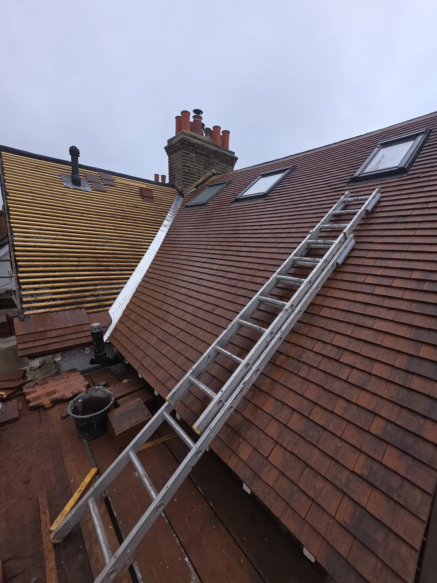 Pitched roof tiling and Velux installation in progress — SW London roofers